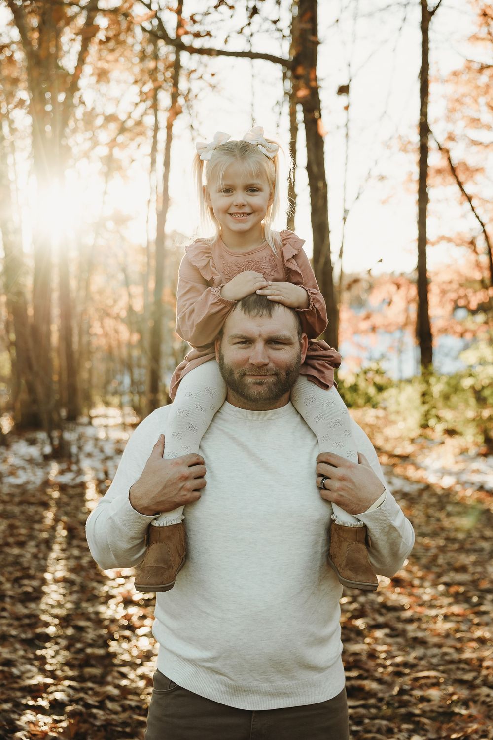 A joyful moment captured in an autumn forest with golden sunlight filtering through the trees during a family photoshoot.