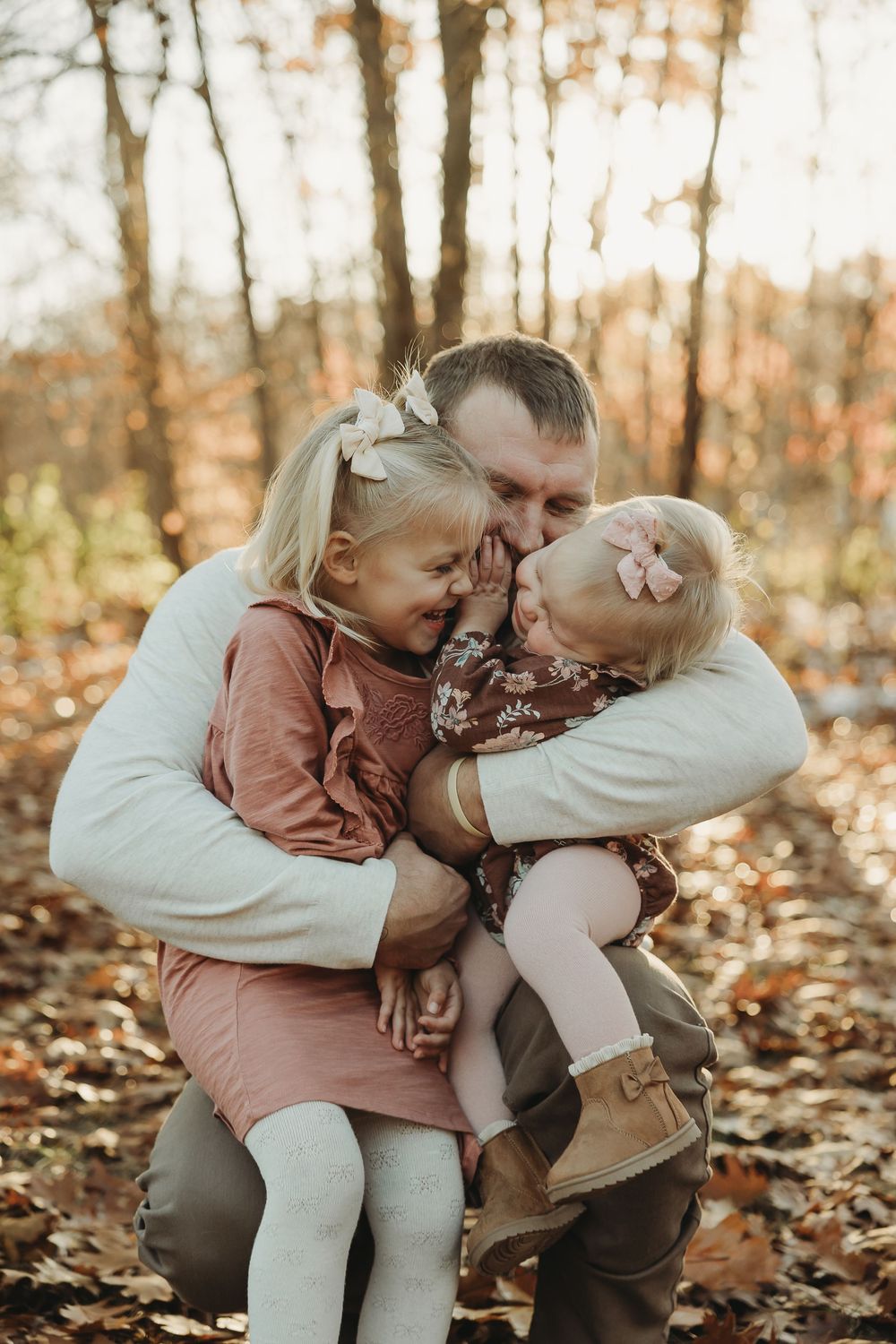 Two small children share a sweet moment while sitting together on fallen leaves in an autumn forest.
