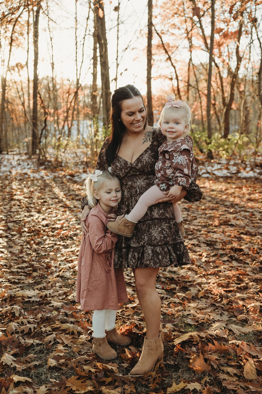 A family shares joyful moments together while playing in autumn leaves during a forest photoshoot.