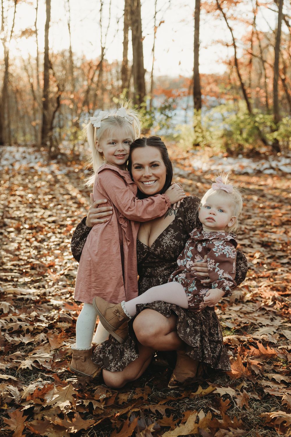 A tender autumn photoshoot in fallen leaves shows joyful moments between parent and child in matching brown outfits.