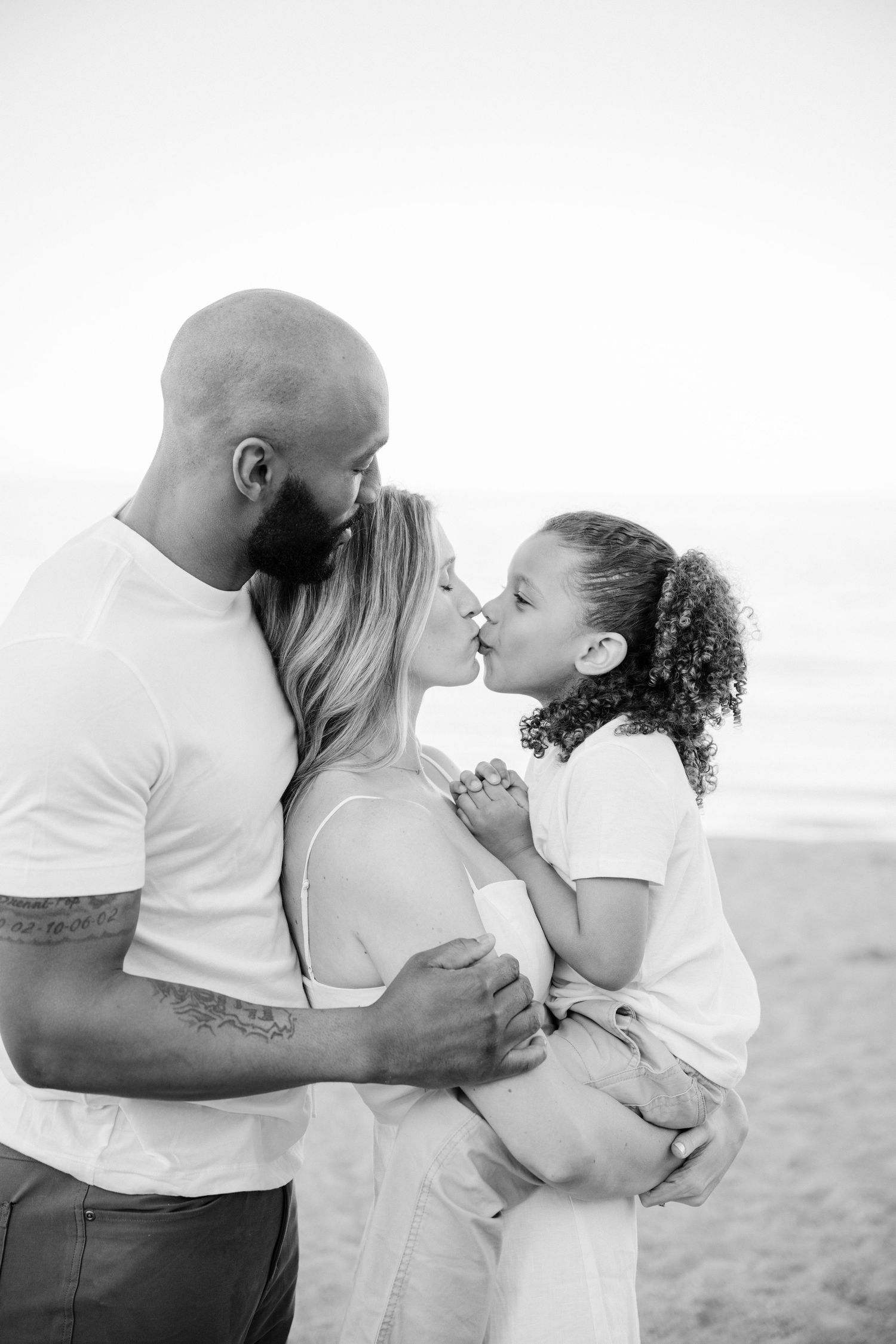 A romantic black and white photo series showing a couple sharing intimate kisses on the beach. - Lake Forest