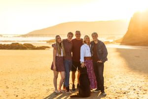 A group photo on a golden beach with sun setting behind coastal mountains.