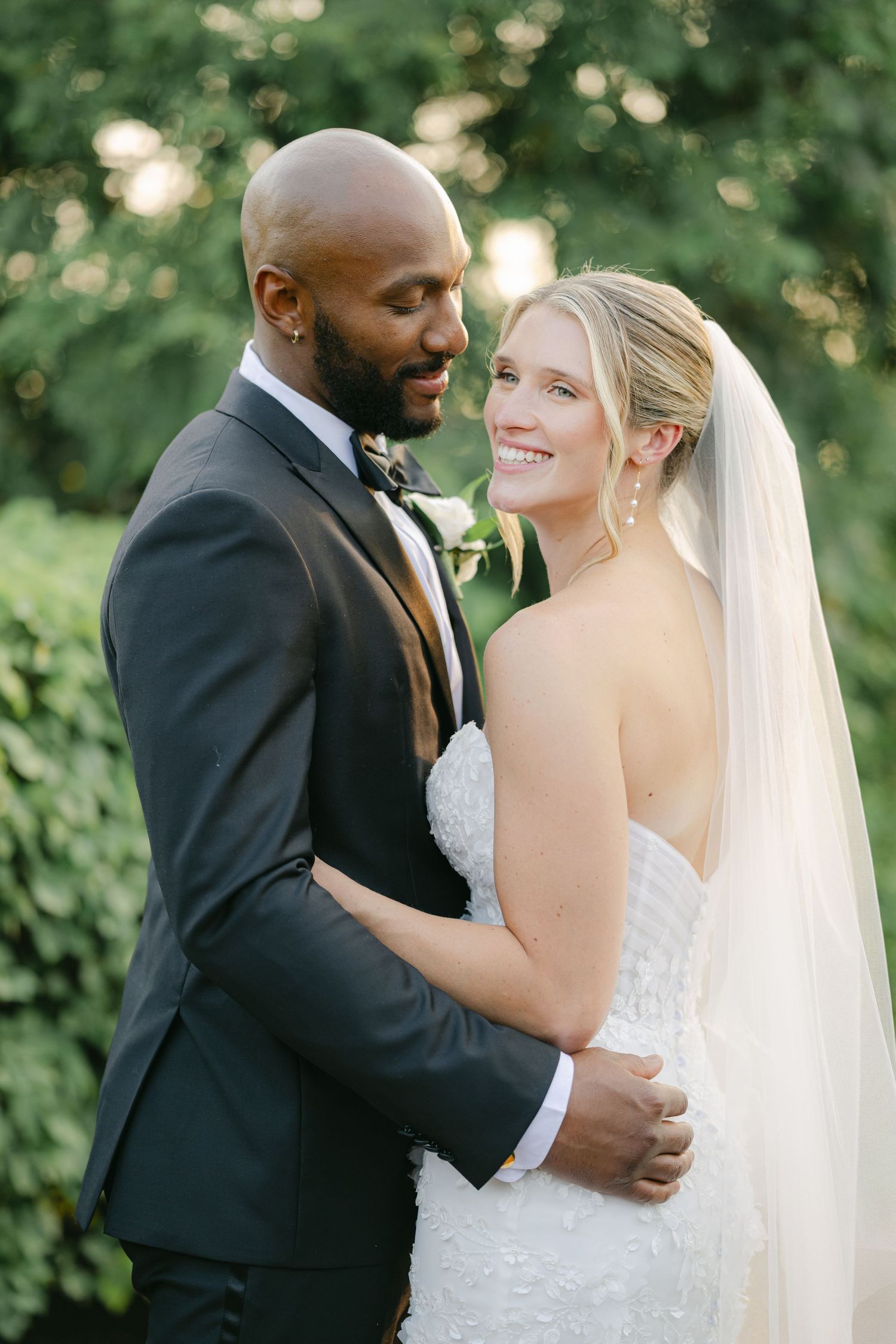 A bride and groom share intimate moments during their outdoor wedding photoshoot in a natural garden setting. - Elawa Farm