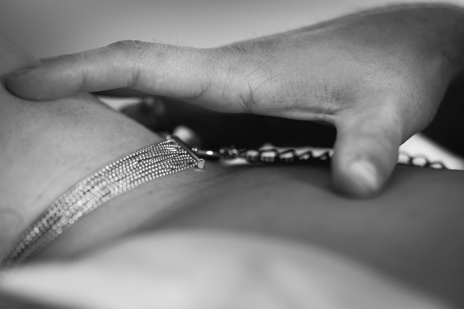 Close-up black and white image of a hand touching delicate fabric with intricate details.