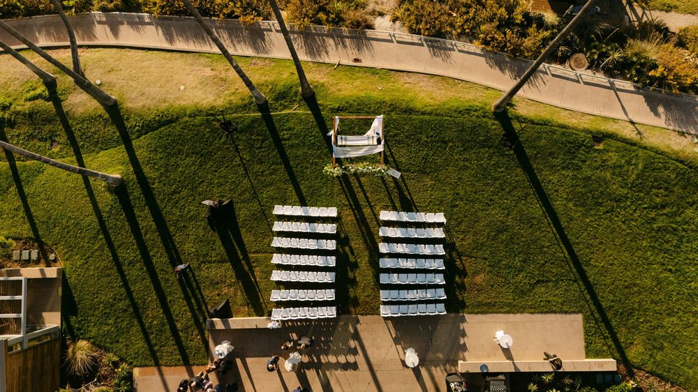 Aerial view of ski lift chairs casting shadows over green summer mountain slopes and hiking trails.