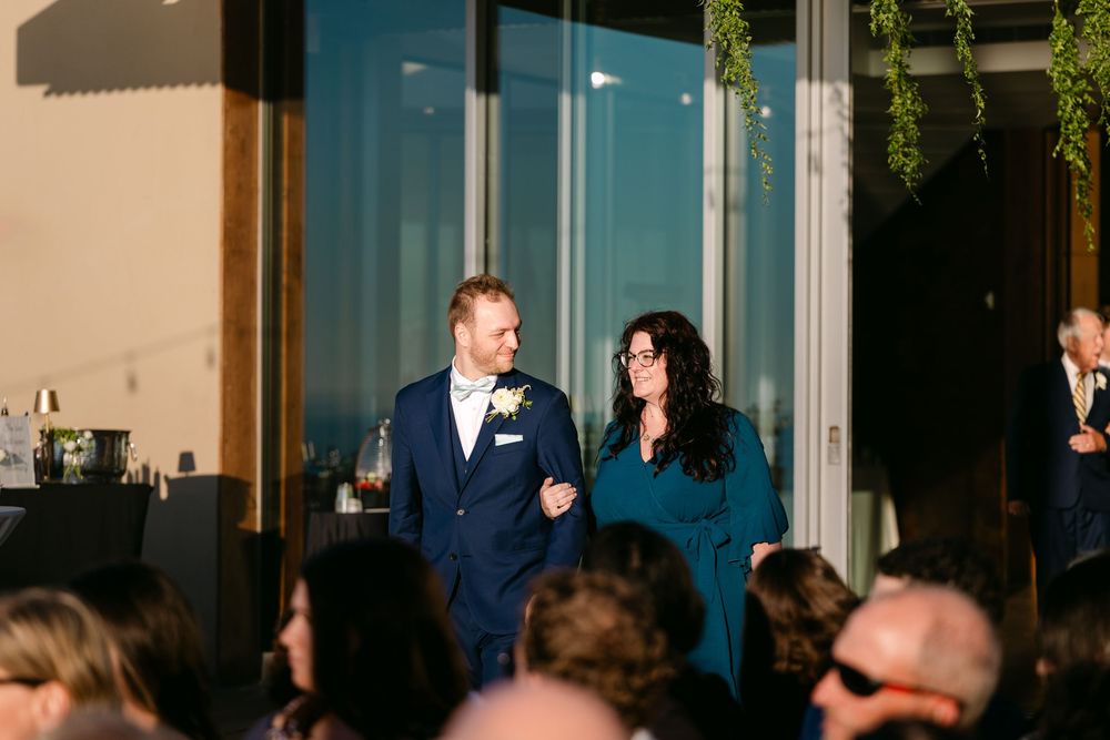 Elegant wedding reception gathering at a modern venue with floor-to-ceiling windows and natural light.