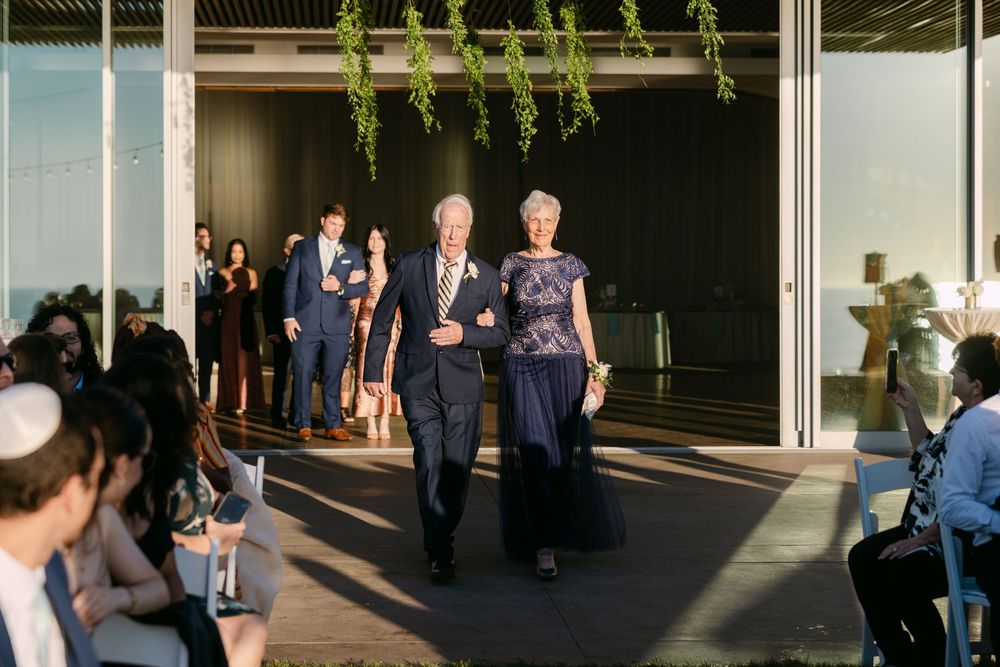Evening wedding celebration in a modern venue with guests socializing in natural light and shadows.