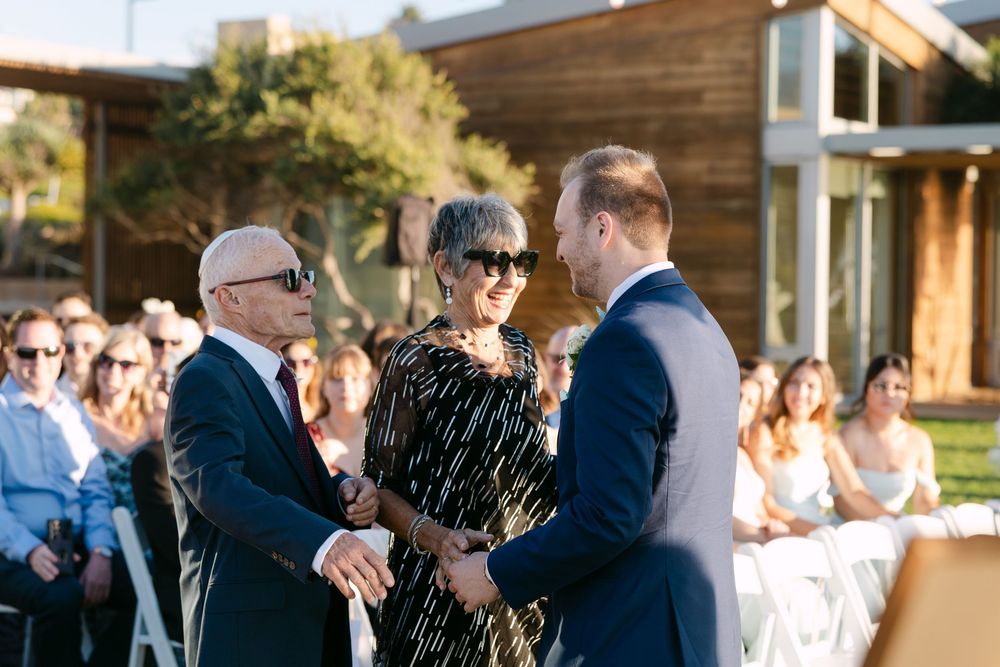 Wedding guests gather outdoors at a scenic venue during golden hour celebrations.