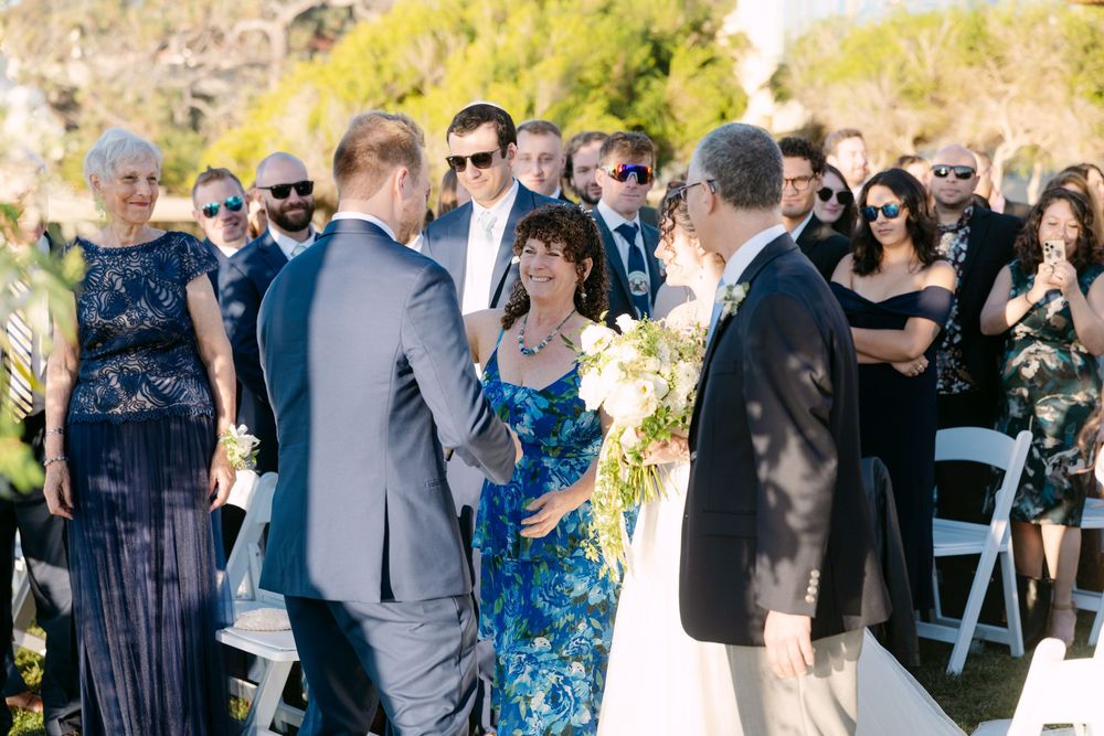 Wedding guests gather outdoors for a joyful celebration in a natural setting during golden hour.