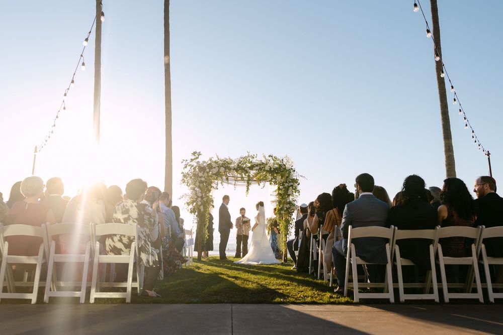 White chairs lined up for an outdoor wedding ceremony with dramatic sunset lighting.