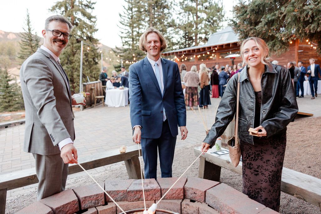 Wedding guests sign a rustic wooden guestbook board at an outdoor mountain venue celebration.