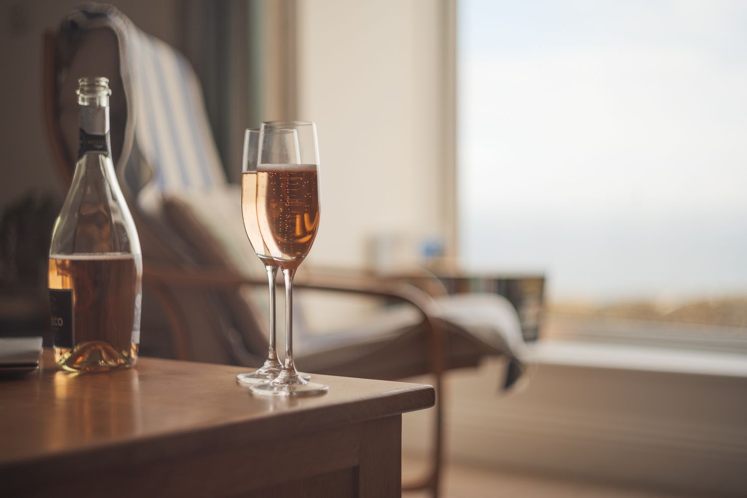 glasses of champagne on table with relaxing chair in background
