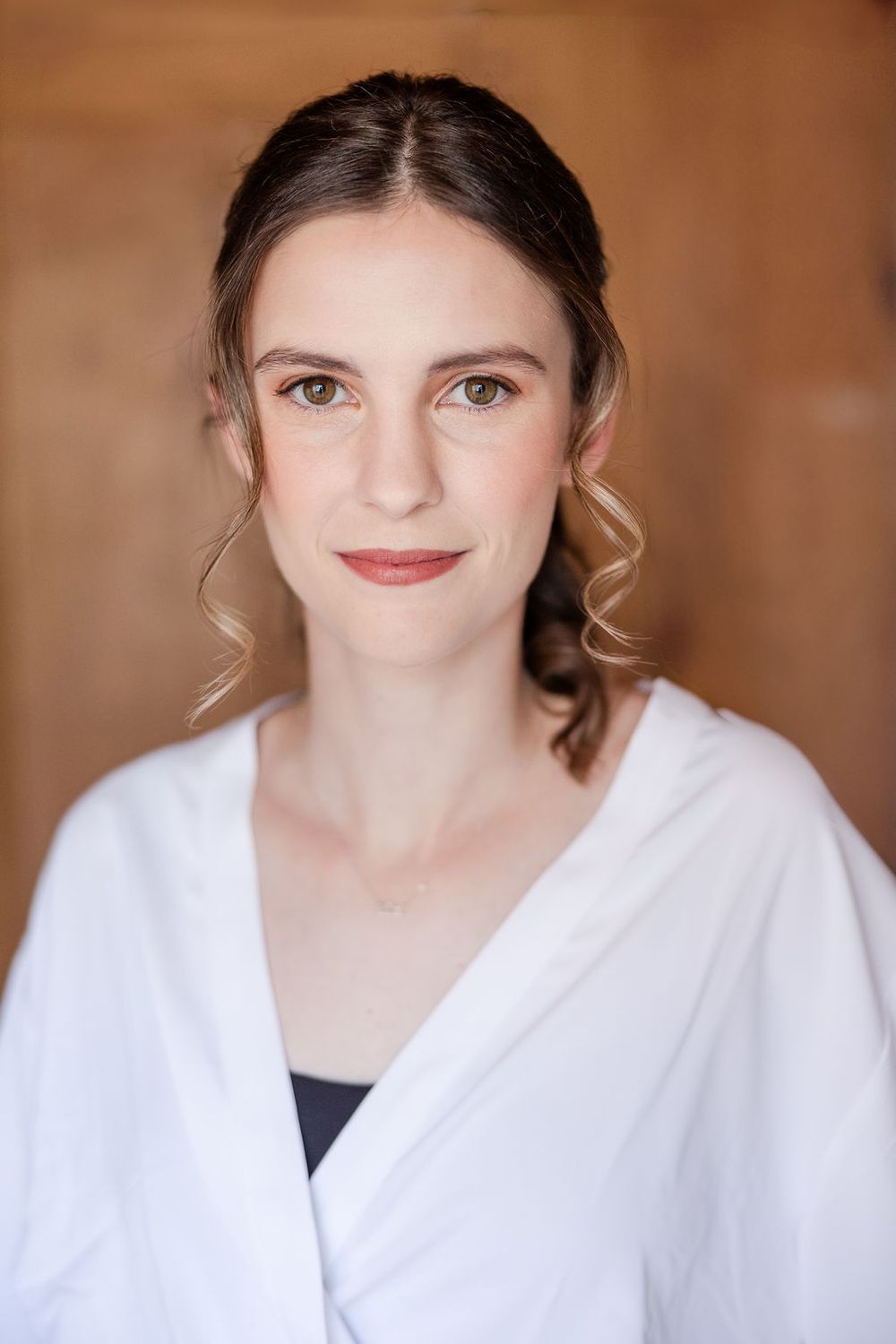 Professional headshot series against warm brown background wearing white robe with natural makeup and styled hair.