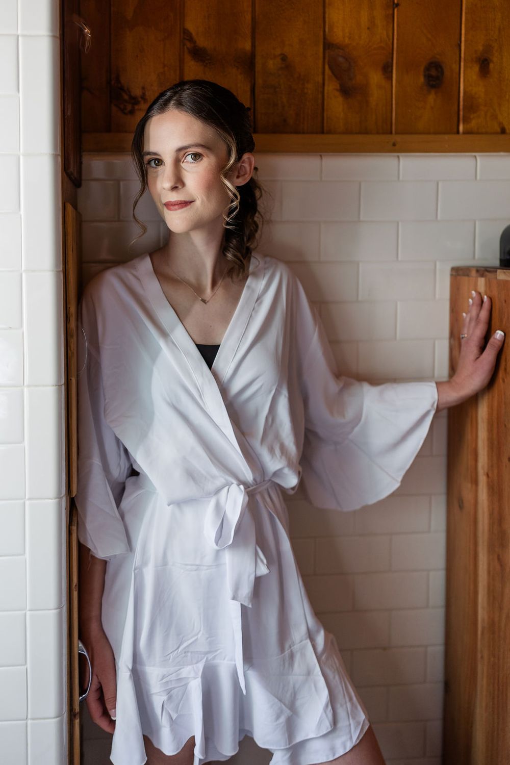 Elegant white wrap blouse with flowing sleeves and bow detail shown against wooden paneled wall.