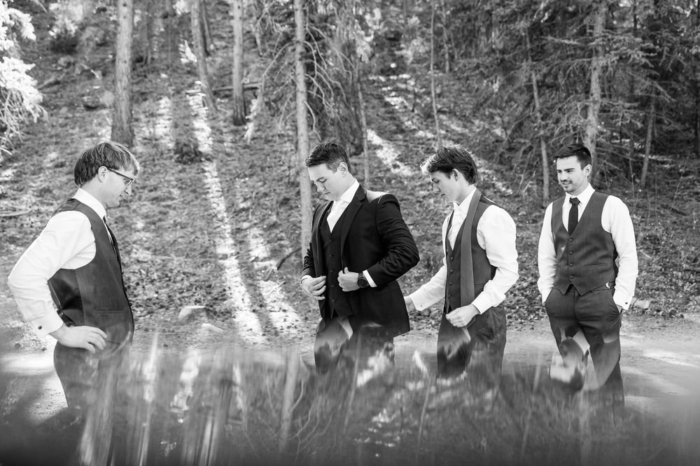 Wedding party walks through a misty forest path in formal attire.
