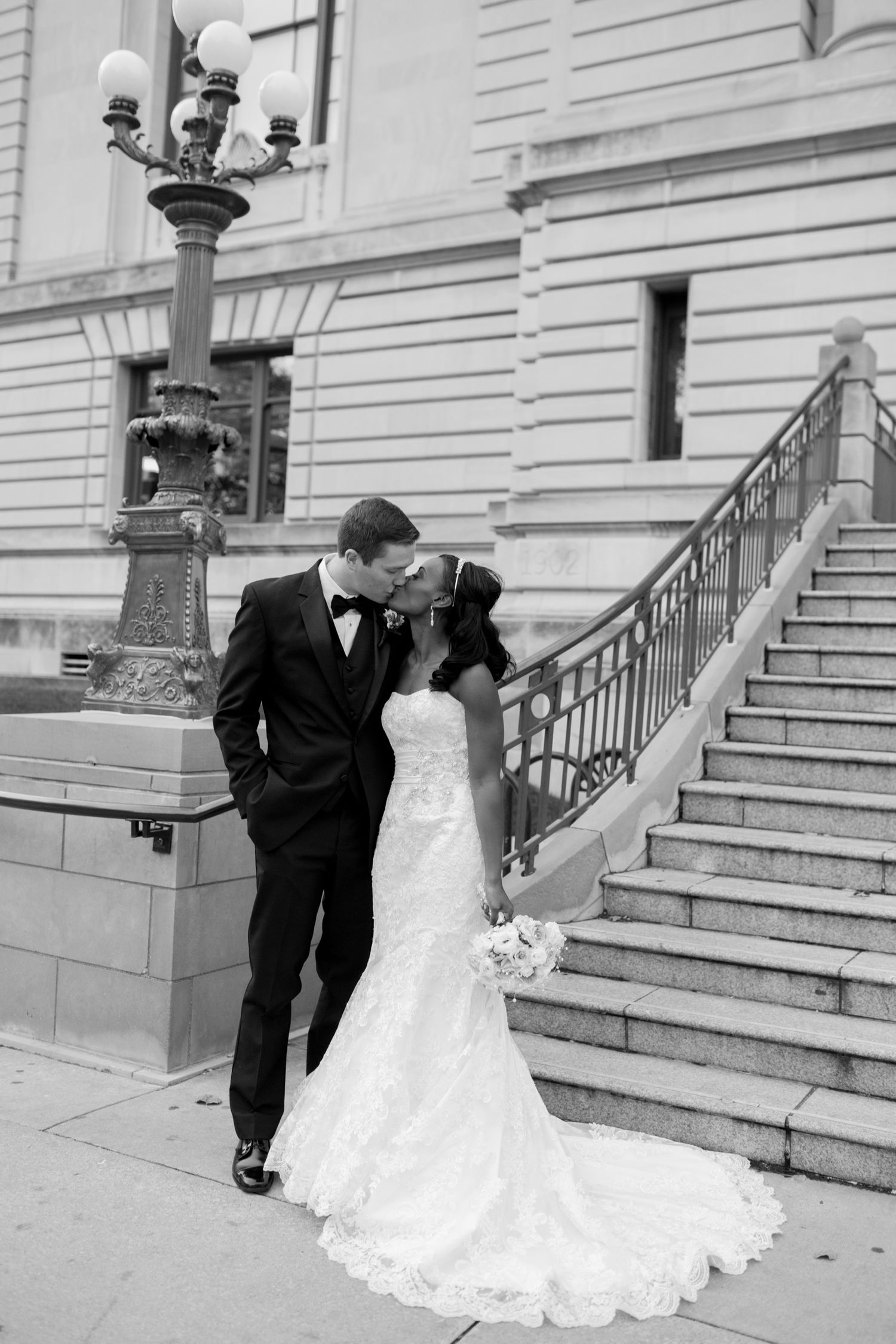 A sequence of four black and white wedding photos showing a couple descending stone steps in formal attire.