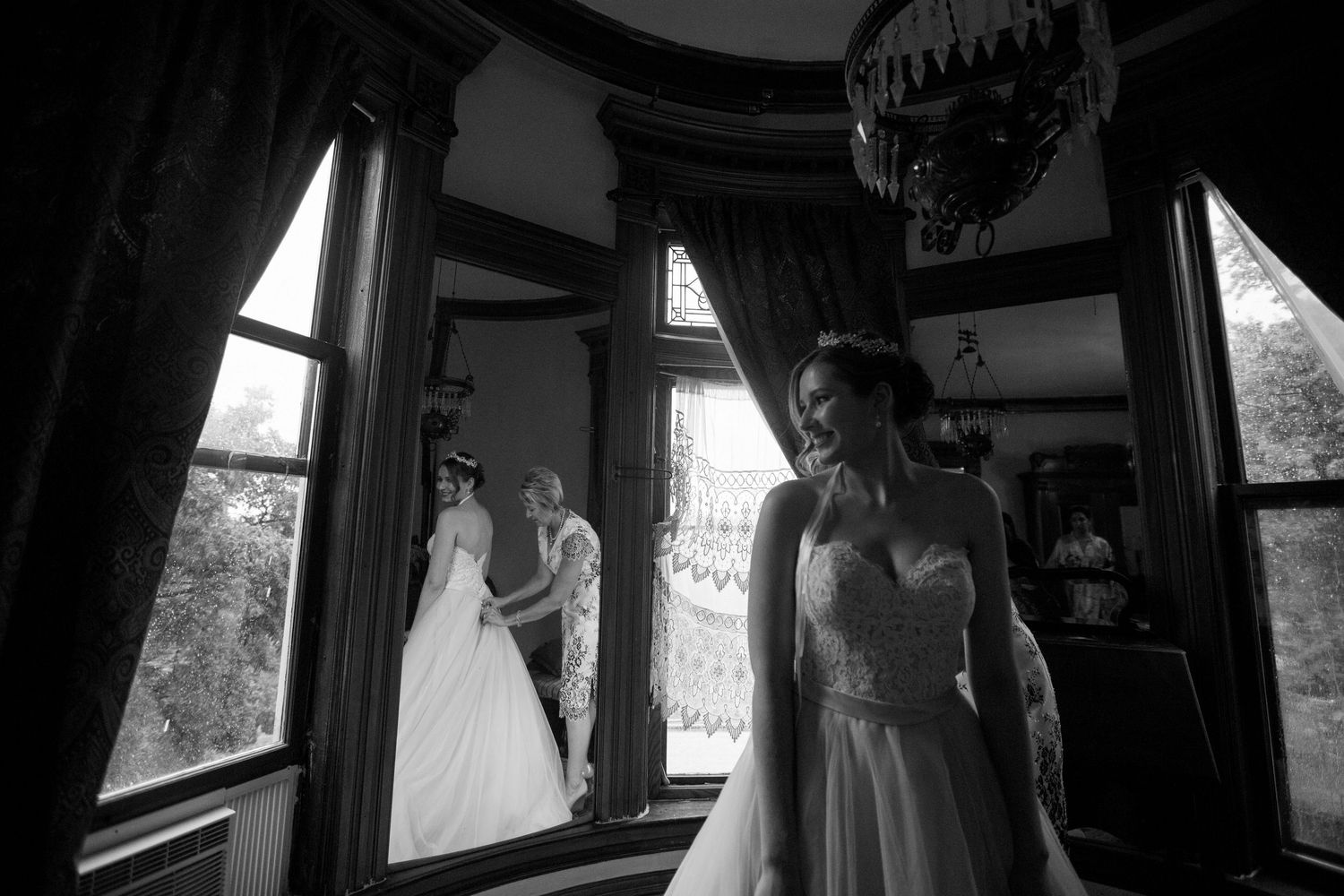 An artistic black and white wedding photo taken through vintage windows with dramatic lighting.