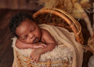 Peaceful newborn baby sleeping in a cozy wicker basket lined with fluffy cream fur.