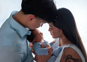 Loving parents tenderly touching foreheads with their newborn baby in an intimate close-up photo.