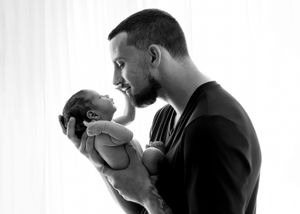 Black and white portrait of a father gazing lovingly at his newborn baby.