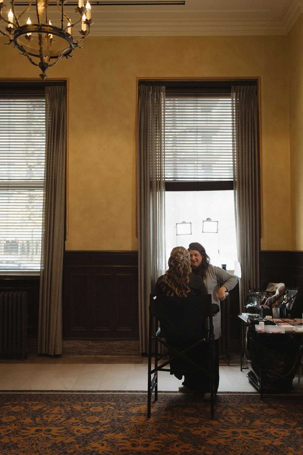 Elegant room with dark wood paneling, ornate chandeliers, and large windows letting in natural light.