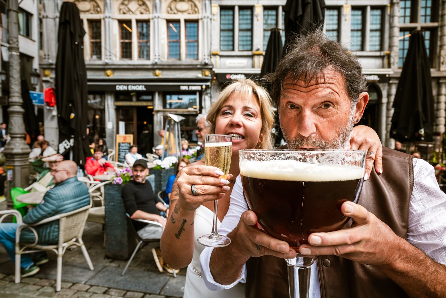 Trouwkoppel geniet van champagne en bier op historisch plein in Antwerpen, spontaan vastgelegd door Bart Boodts met focus op beleving.