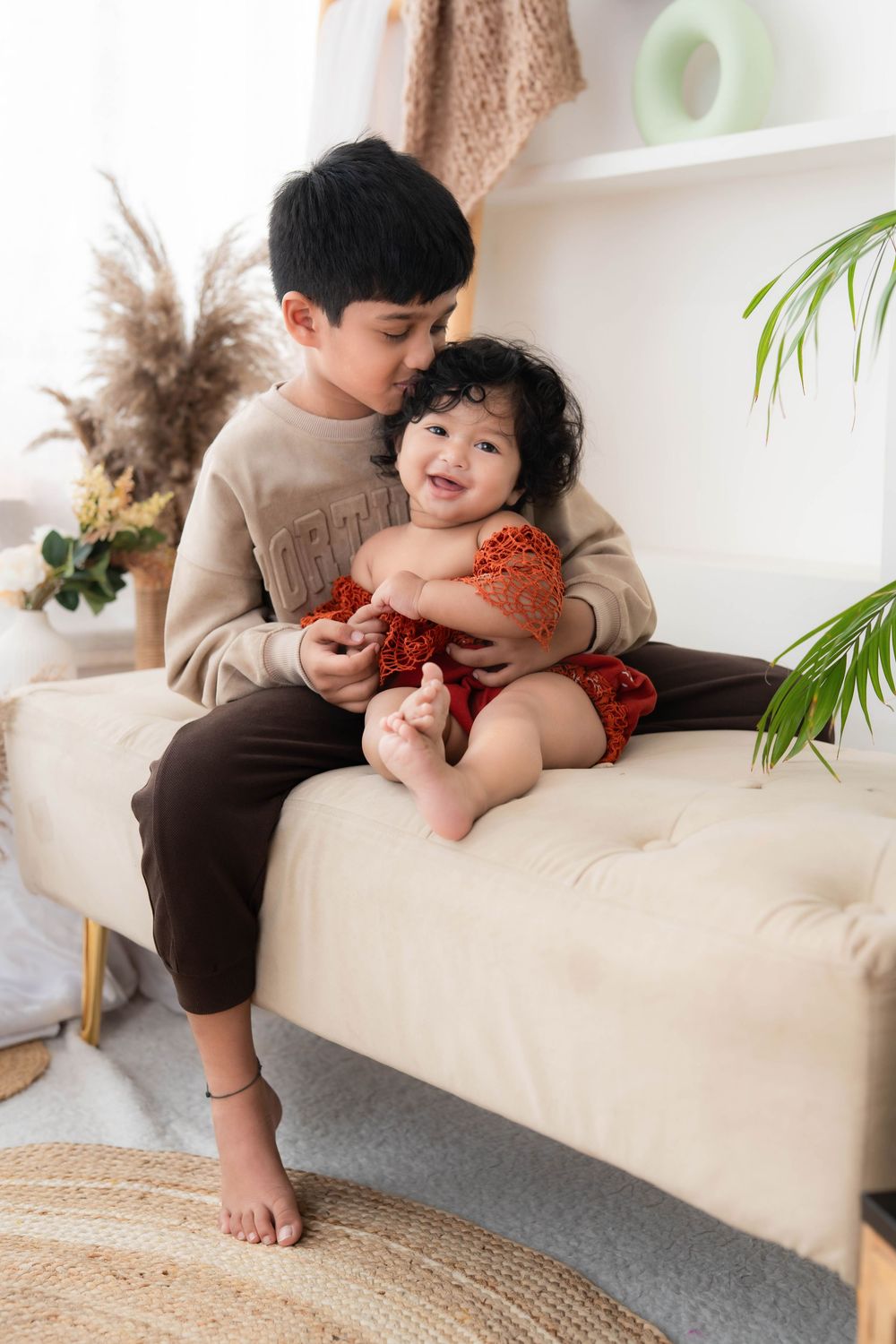Elder sibling holding baby during studio sibling toddler photoshoot in Hyderabad