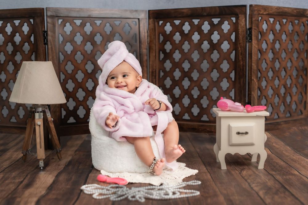 Toddler girl sitting on stool in pink outfit during studio toddler photoshoot in Hyderabad