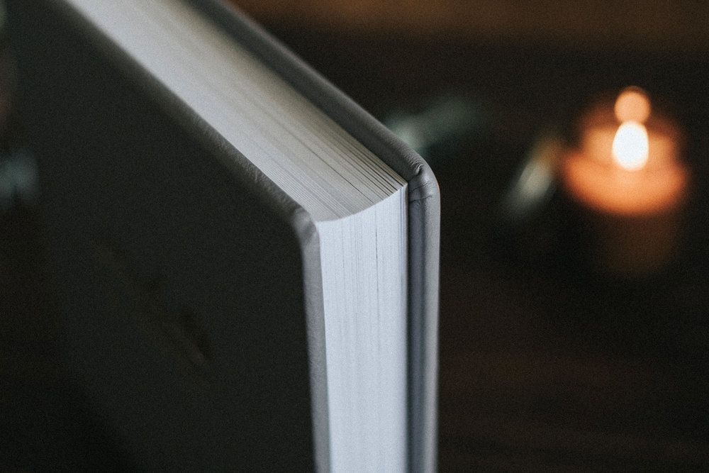 Close up of white photo album pages illuminated by soft candlelight.