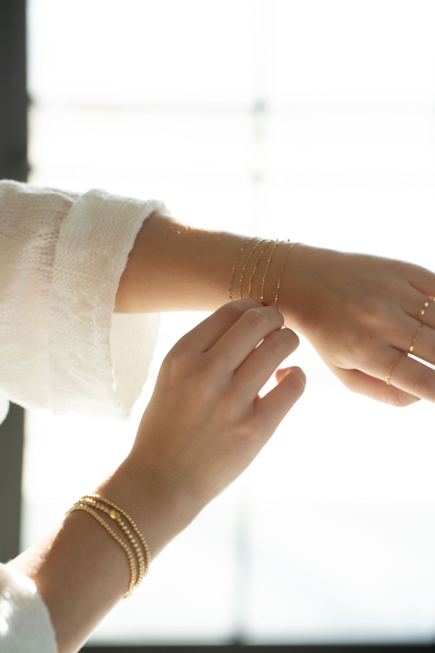 Close-up view of hands wearing delicate gold bracelets and rings against soft natural light during a branding session in Arlington Heights