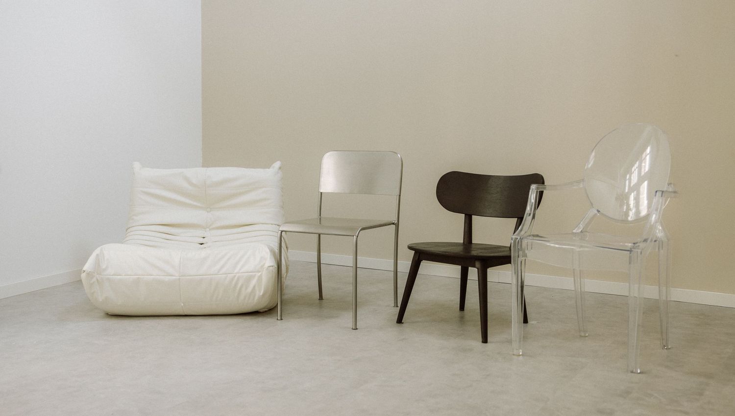 Modern living room interior with white leather sofa, dark chair and minimalist decor against neutral walls.