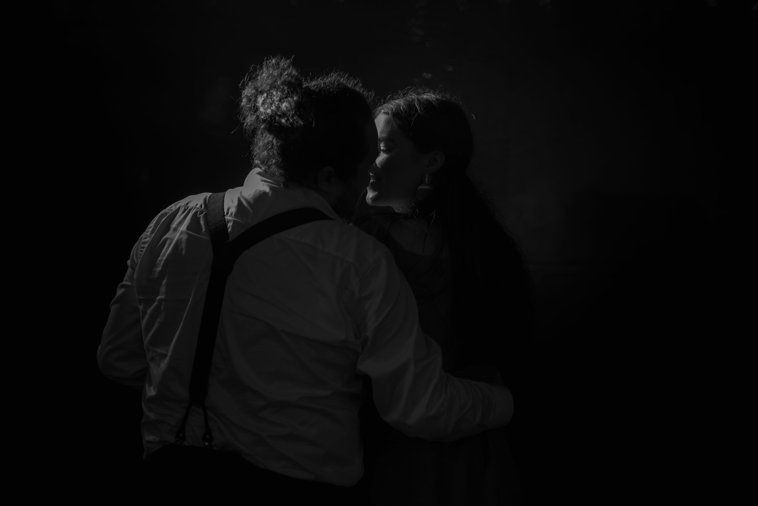A silhouetted couple dances together in an intimate embrace against a dark background.