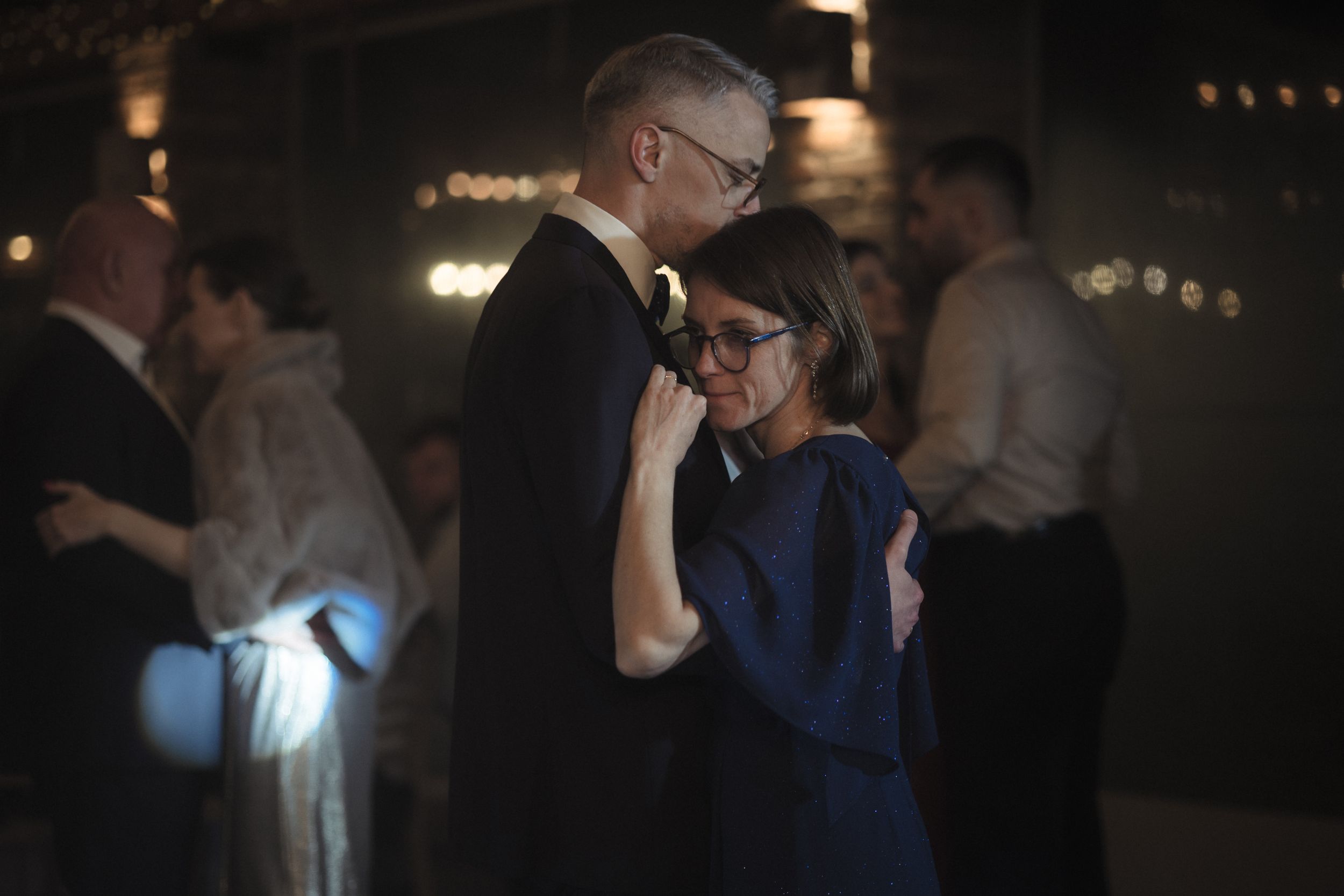 People dancing and socializing at a dimly lit party or nightclub with atmospheric lighting.
