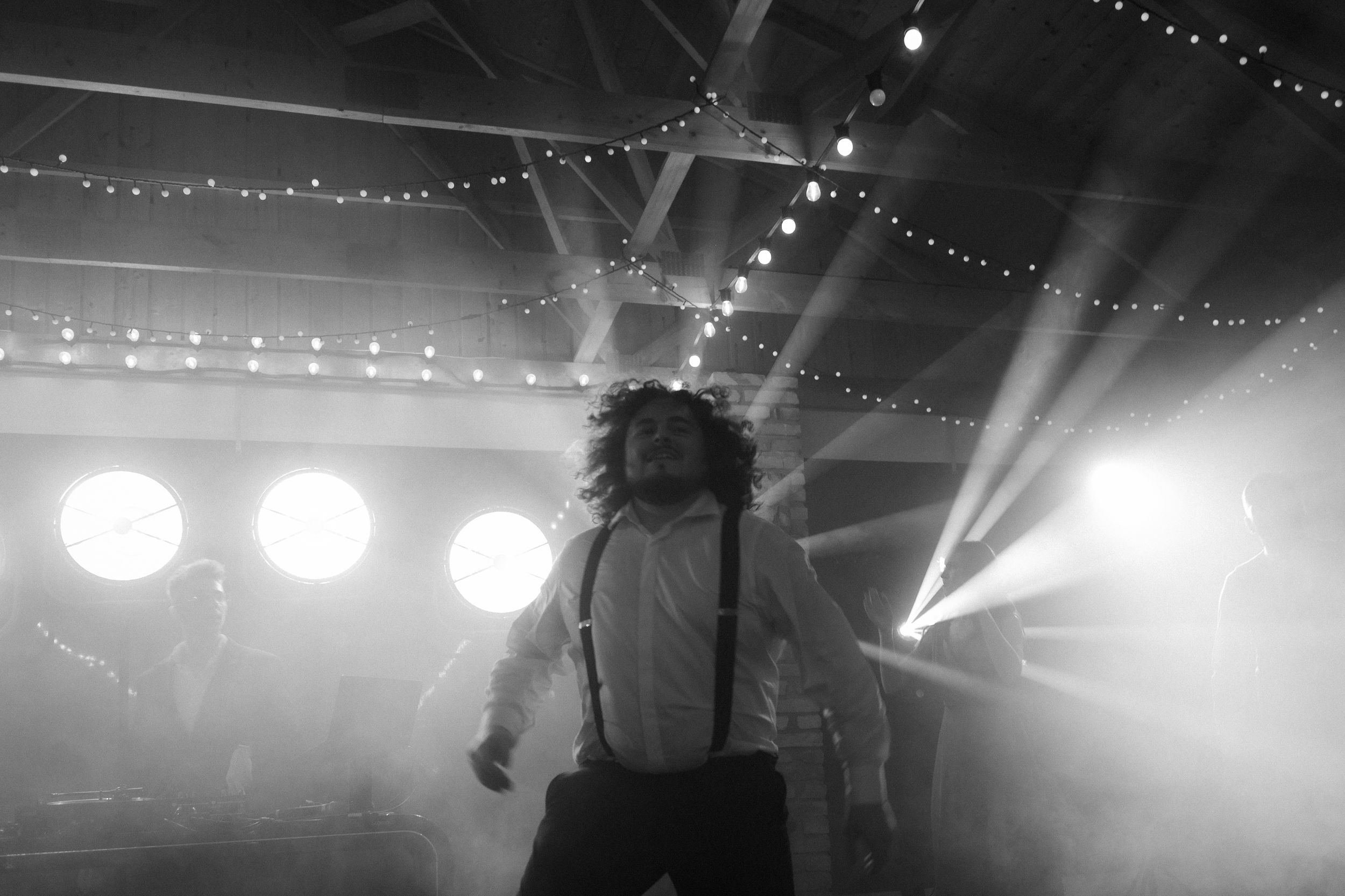 Concert performers on stage illuminated by dramatic spotlights and string lights creating an atmospheric ambiance.