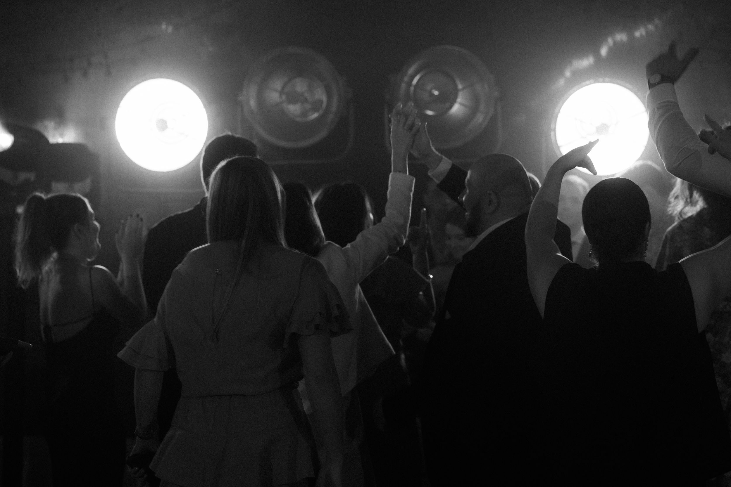 A crowd of silhouetted people stand against a bright full moon in the background during a nighttime event.