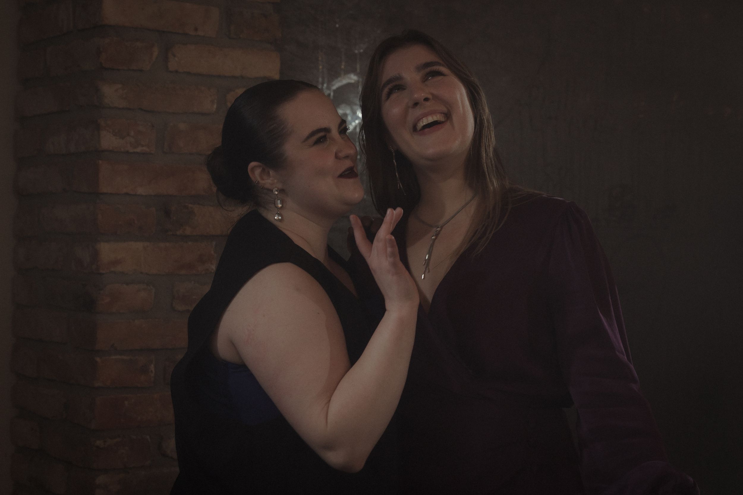 A couple shares a romantic moment while dancing together in front of a brick wall.