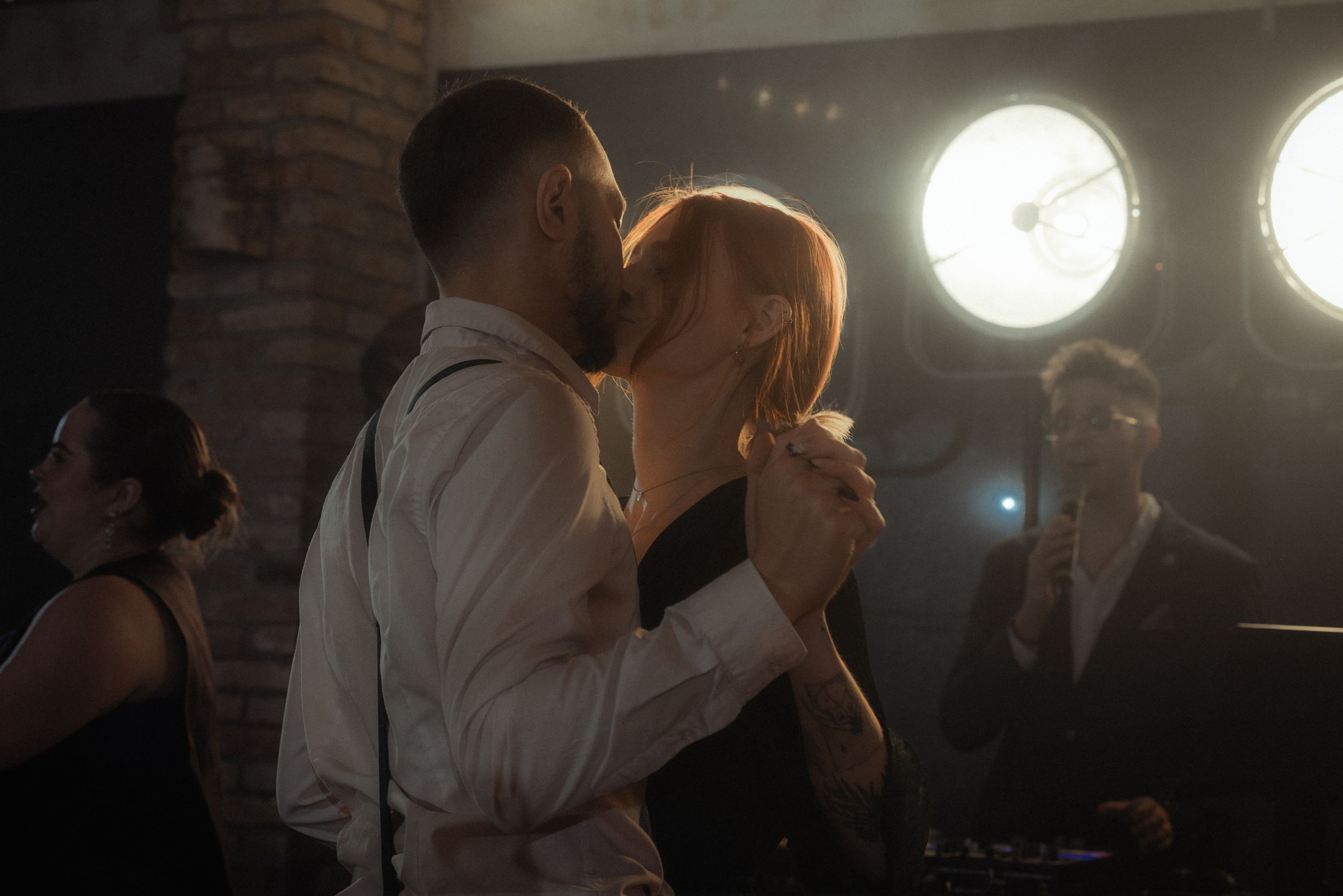 A couple shares a romantic slow dance together under soft lighting at an evening event.
