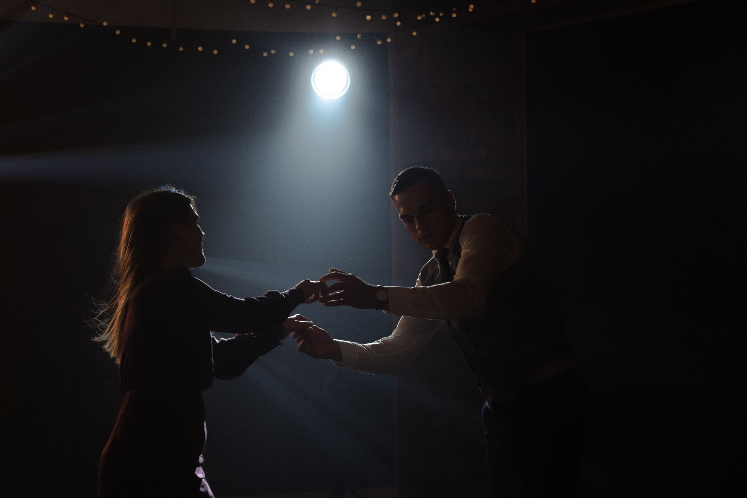 Dramatic silhouettes of dancers performing in dark lighting with spotlights creating atmospheric beams and shadows.