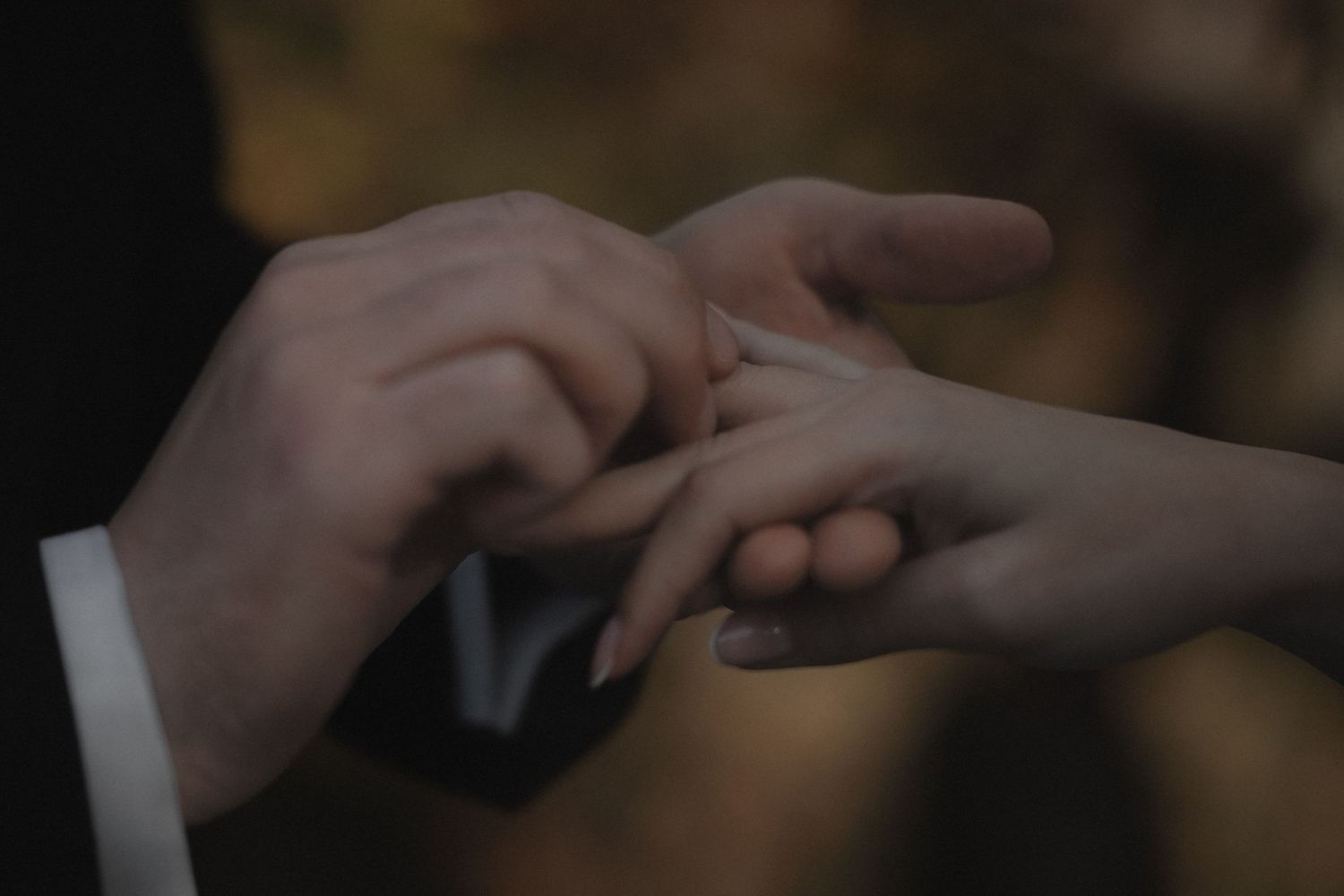 Close-up shot of hands exchanging wedding rings during a romantic ceremony.