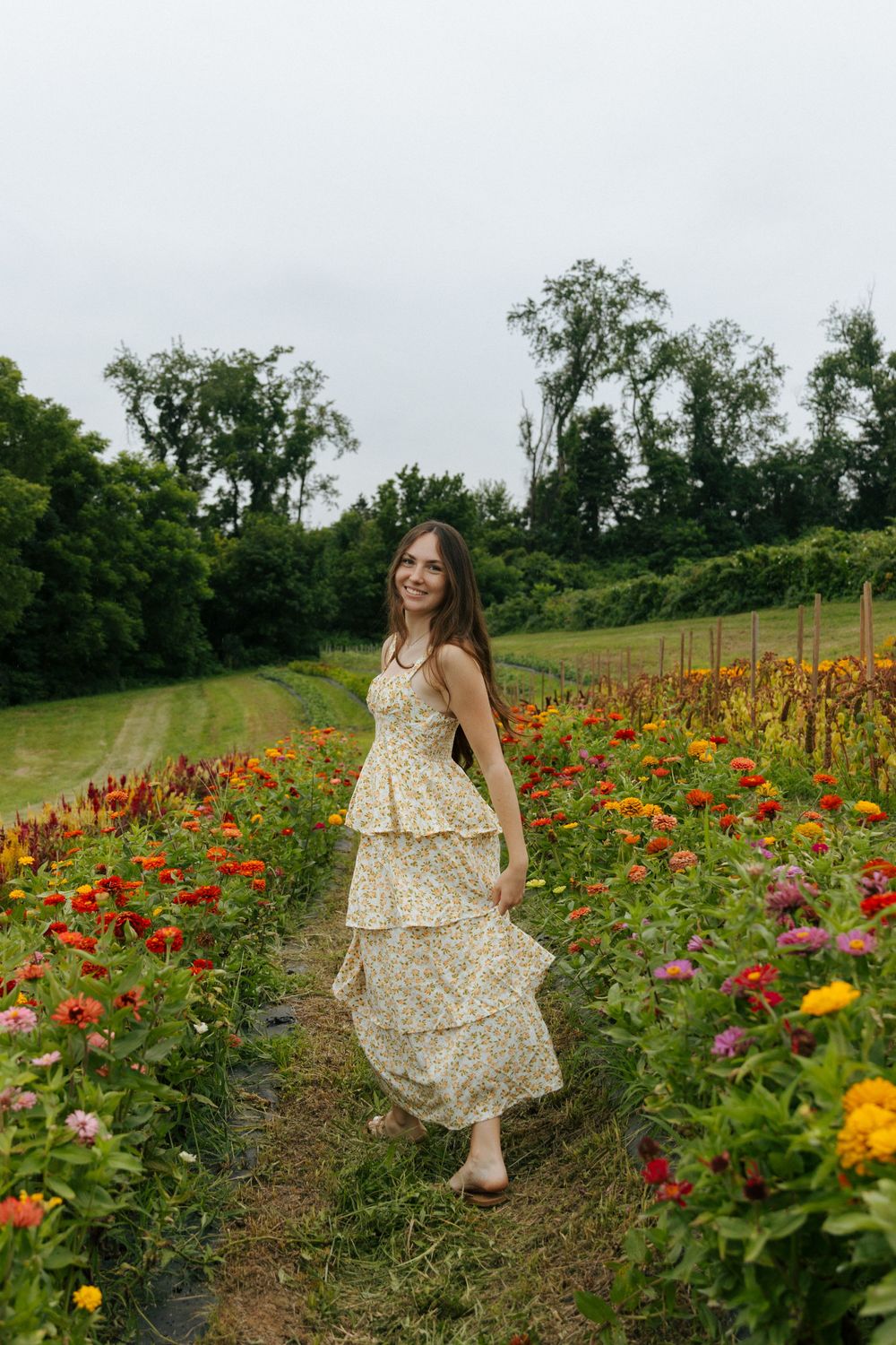 Woman in yellow floral dress twirls through a vibrant flower field.