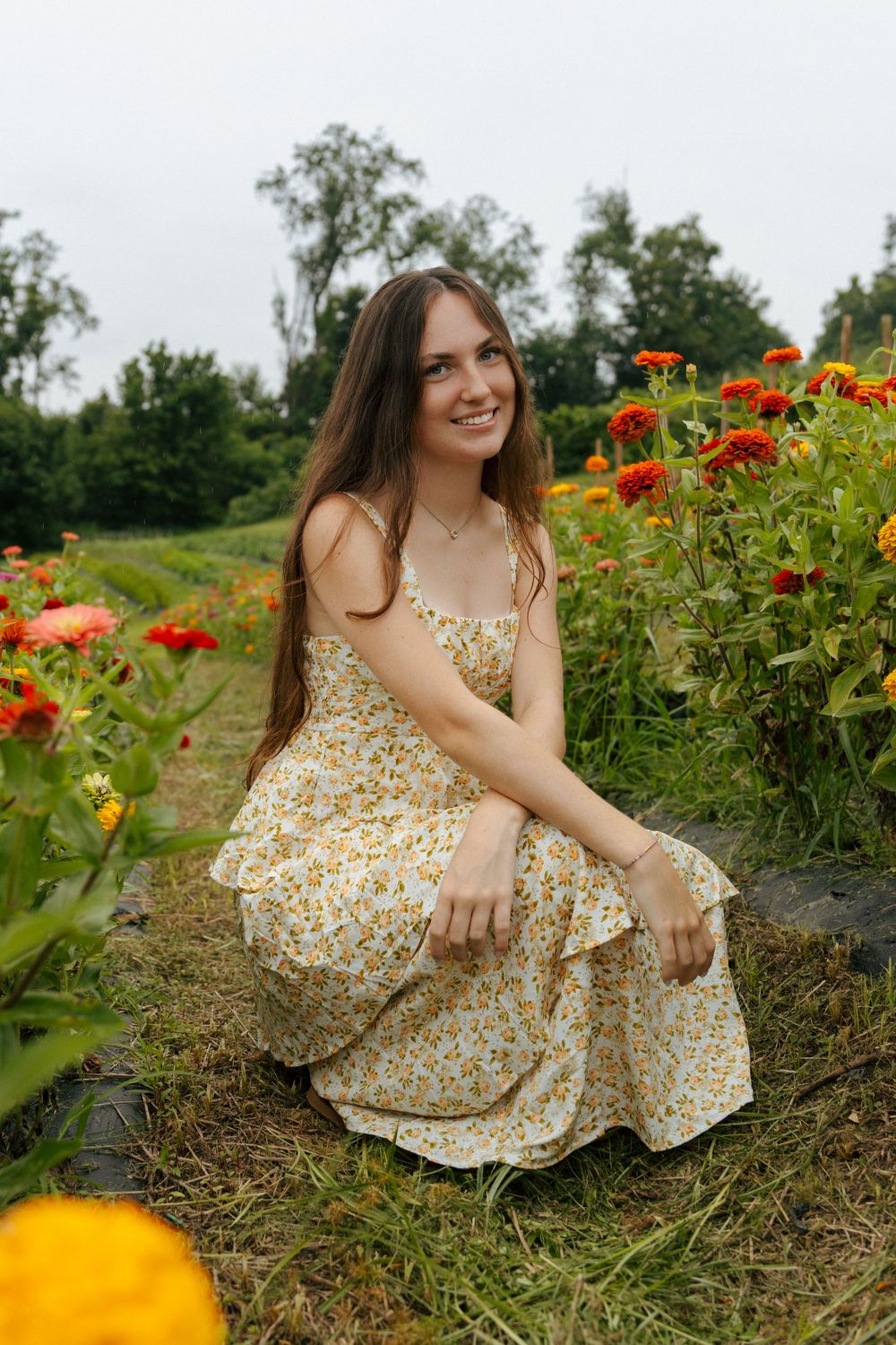 A yellow floral dress stands out against a backdrop of colorful blooming flowers in a garden setting.
