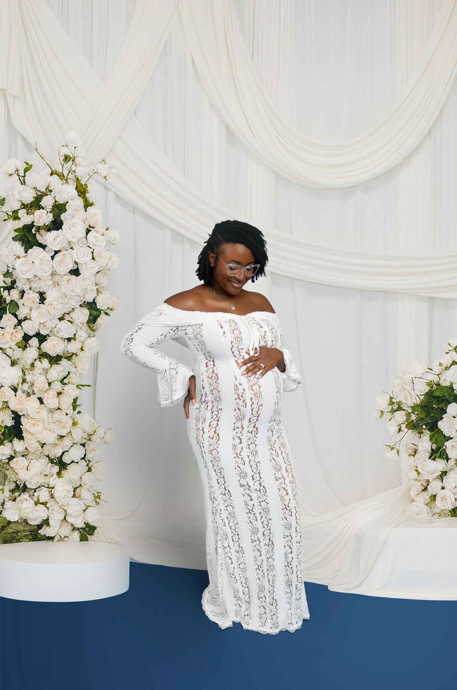 A series of four photos showing someone in a white lace dress posing against a white backdrop with floral decorations.