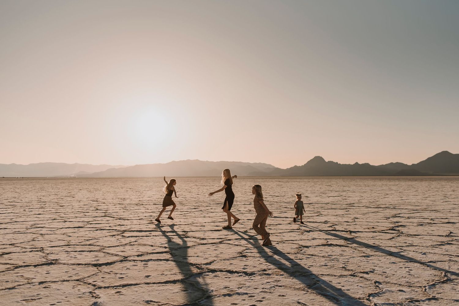 Silhouettes of people walking across salt flats at sunset casting long dramatic shadows.