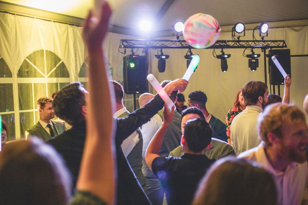 Guests dancing at a lively wedding reception party with colorful glowing lights and festive atmosphere.