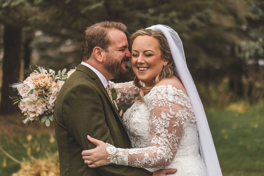A couple shares an intimate moment outdoors during their wedding ceremony wearing traditional formal attire.