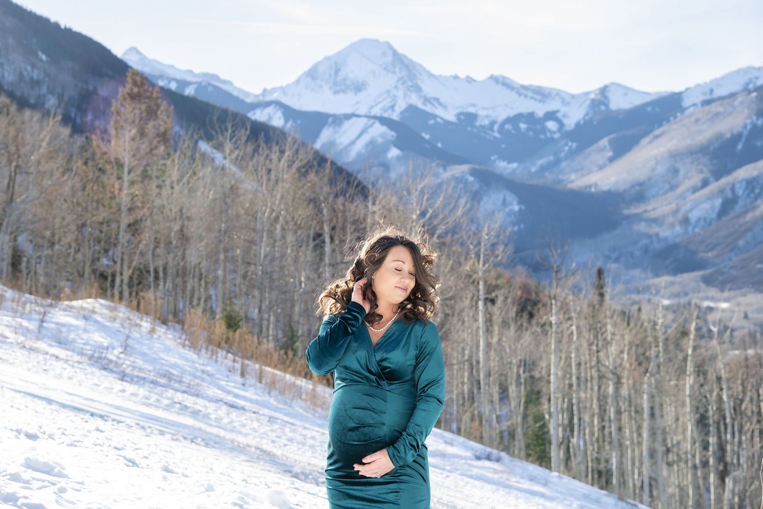 Glamorous maternity photos in winter with snowy mountains in Snowmass Colorado