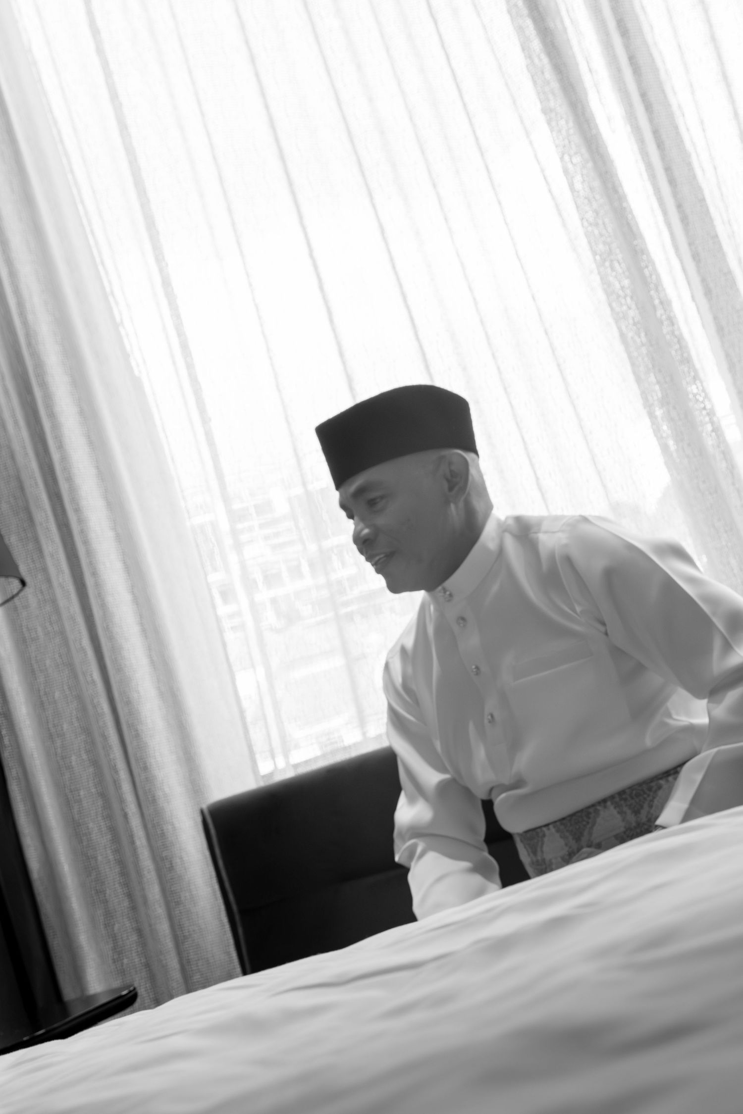 Man in traditional Muslim attire reading during a religious ceremony.