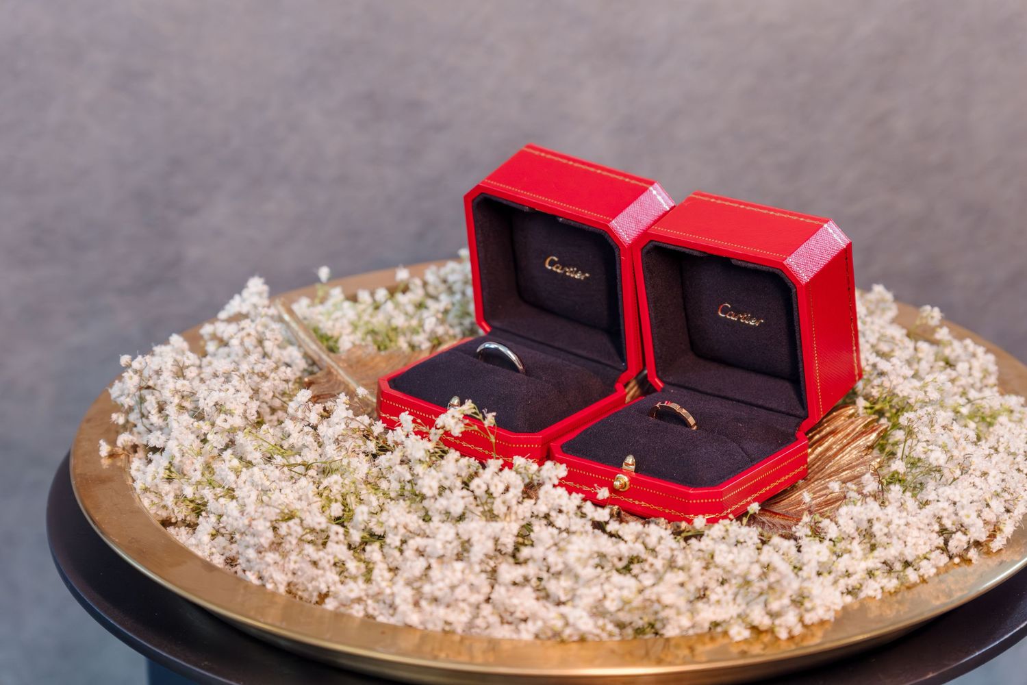 Red engagement ring boxes displayed on scattered white flower petals.