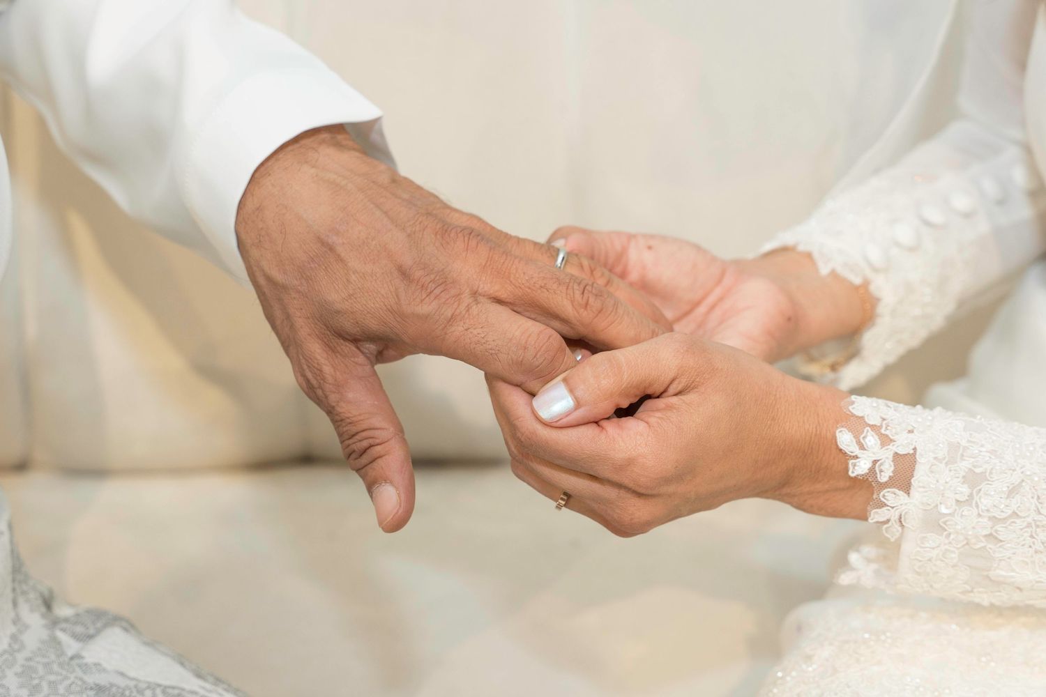 Close up of hands during a traditional wedding ceremony as a ring is being exchanged.