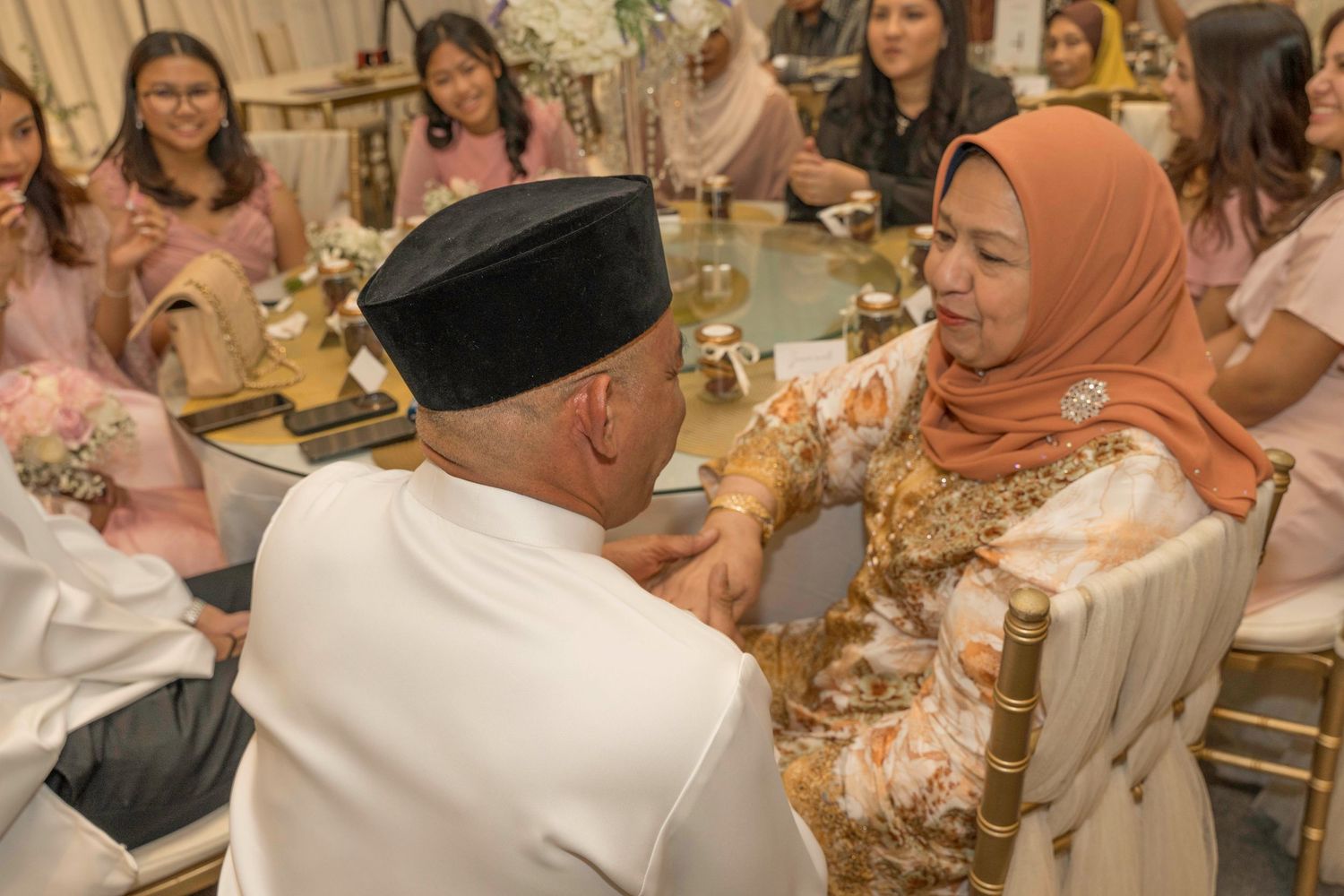 Wedding celebration with guests seated at decorated tables in a formal banquet setting.